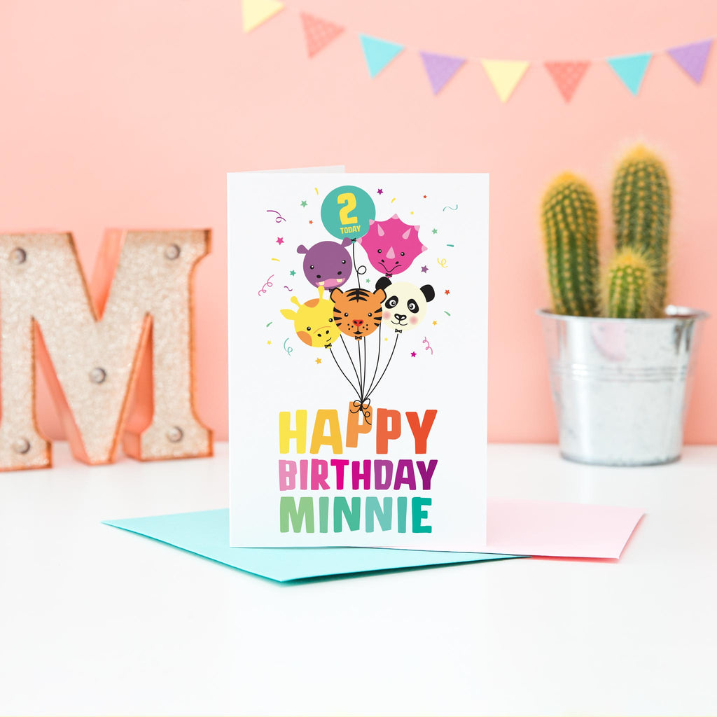 Girls happy birthday card in bright colours with a cute bunch of animal faced balloons including a giraffe, tiger, panda, hippo and dinosaur. The card includes personalised name and age.