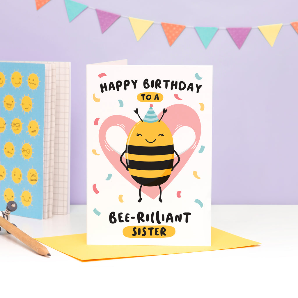 Happy birthday to a bee-rilliant Sister. A cute and punny card featuring a happy bee wearing a party hat to represent Auntie, with a pink heart in the background and a sprinkle of confetti.
