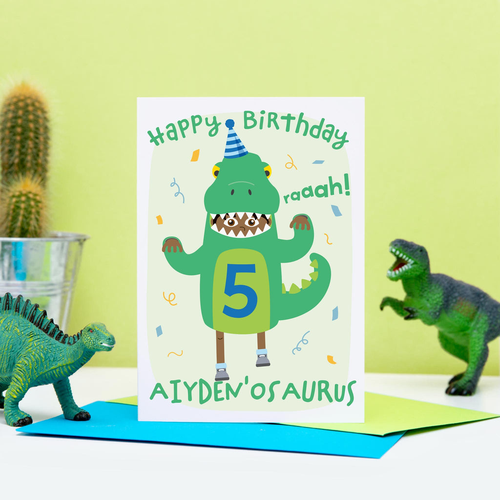 Birthday card with cute boy dressed in a dinosaur costume. Personalised for any name and age, as well age eye colour, skin colour and hair colour. Shown age five.