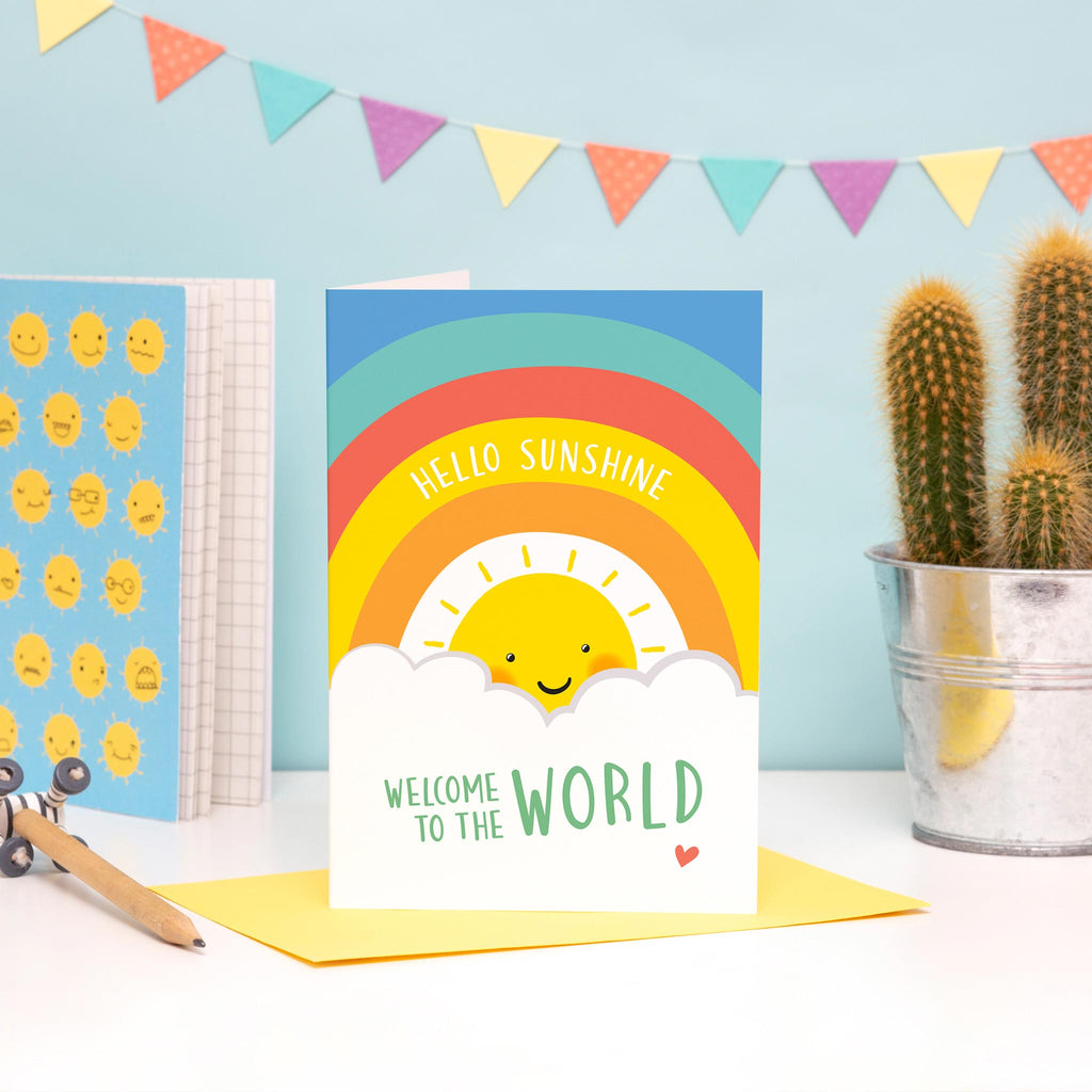 Sun, clouds and colourful rainbow on this card with the words Hello sunshine, welcome to the world