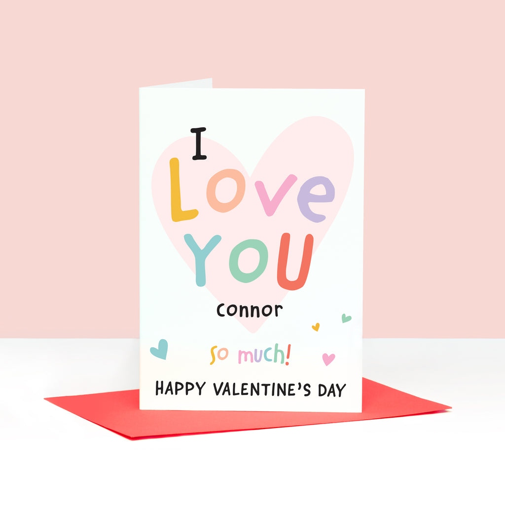 A colourful pastel card with the words I love you happy Valentines day, with space for personalising with a name. The card features a light pink heart in the background overlayed by soft multicoloured text.