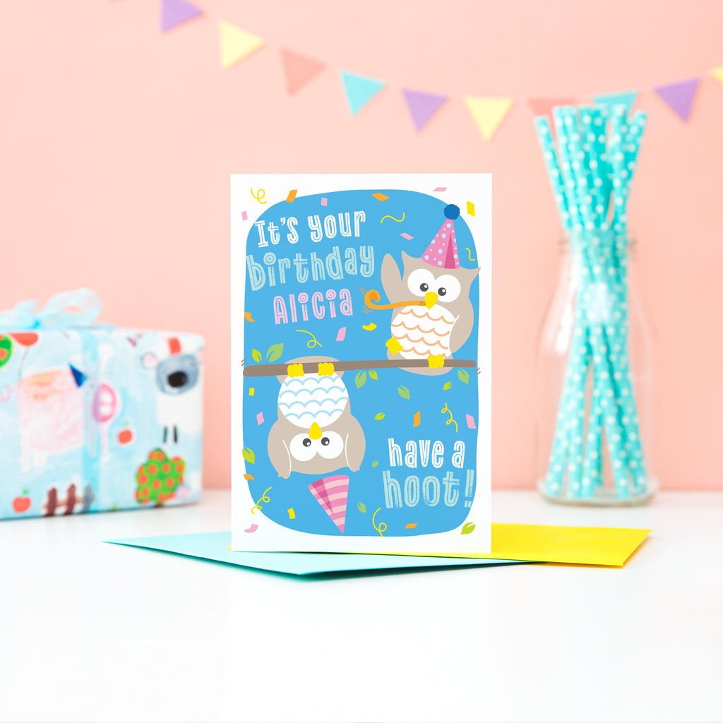 It's your birthday, have a hoot! Pink text on this birthday card with two owls with party hats and streamers. This fun card is personalised with any name.