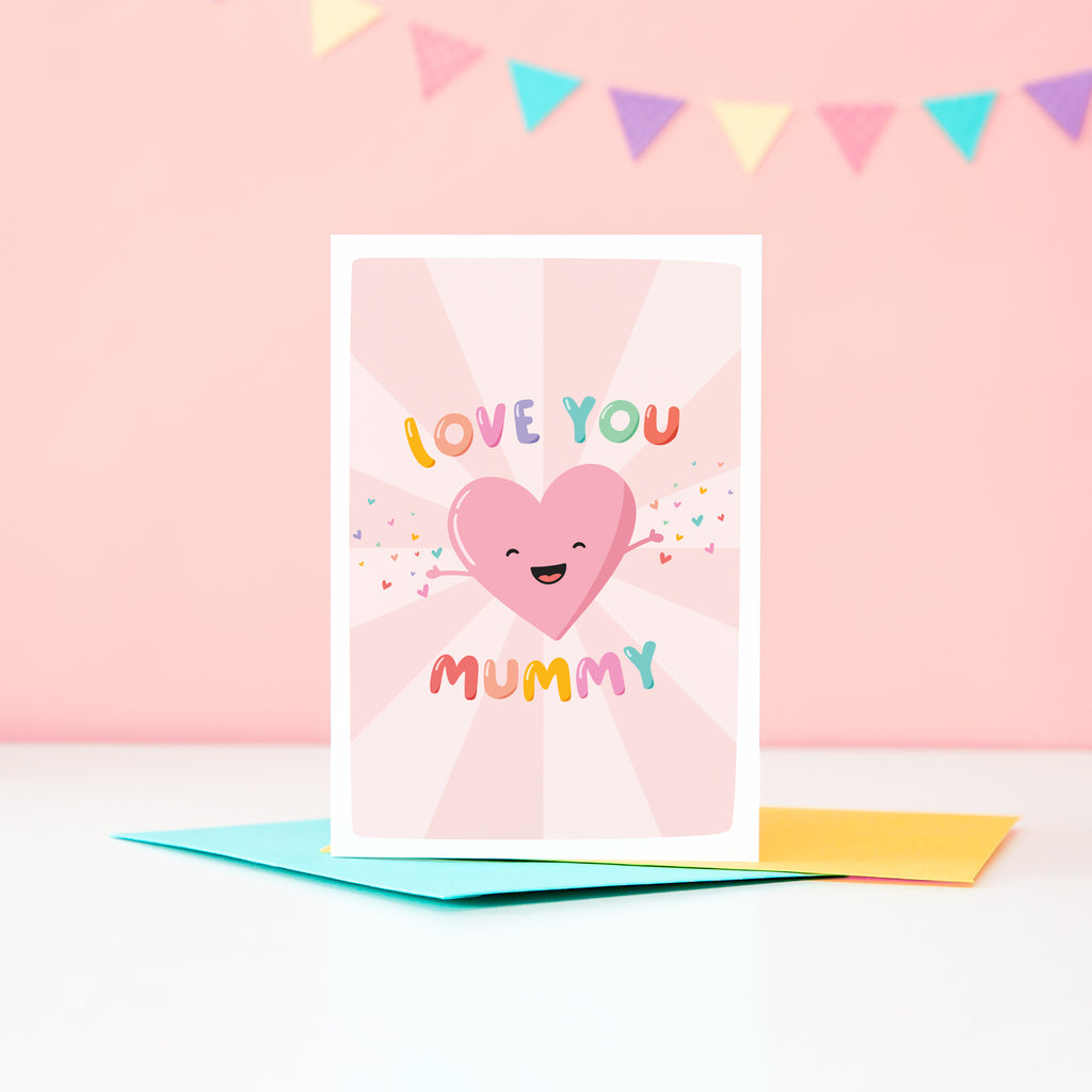 A cute and colourful card featuring a happy love heart with arms open wide throwing a sprinkle of smaller colourful love hearts. The card reads love you mummy.