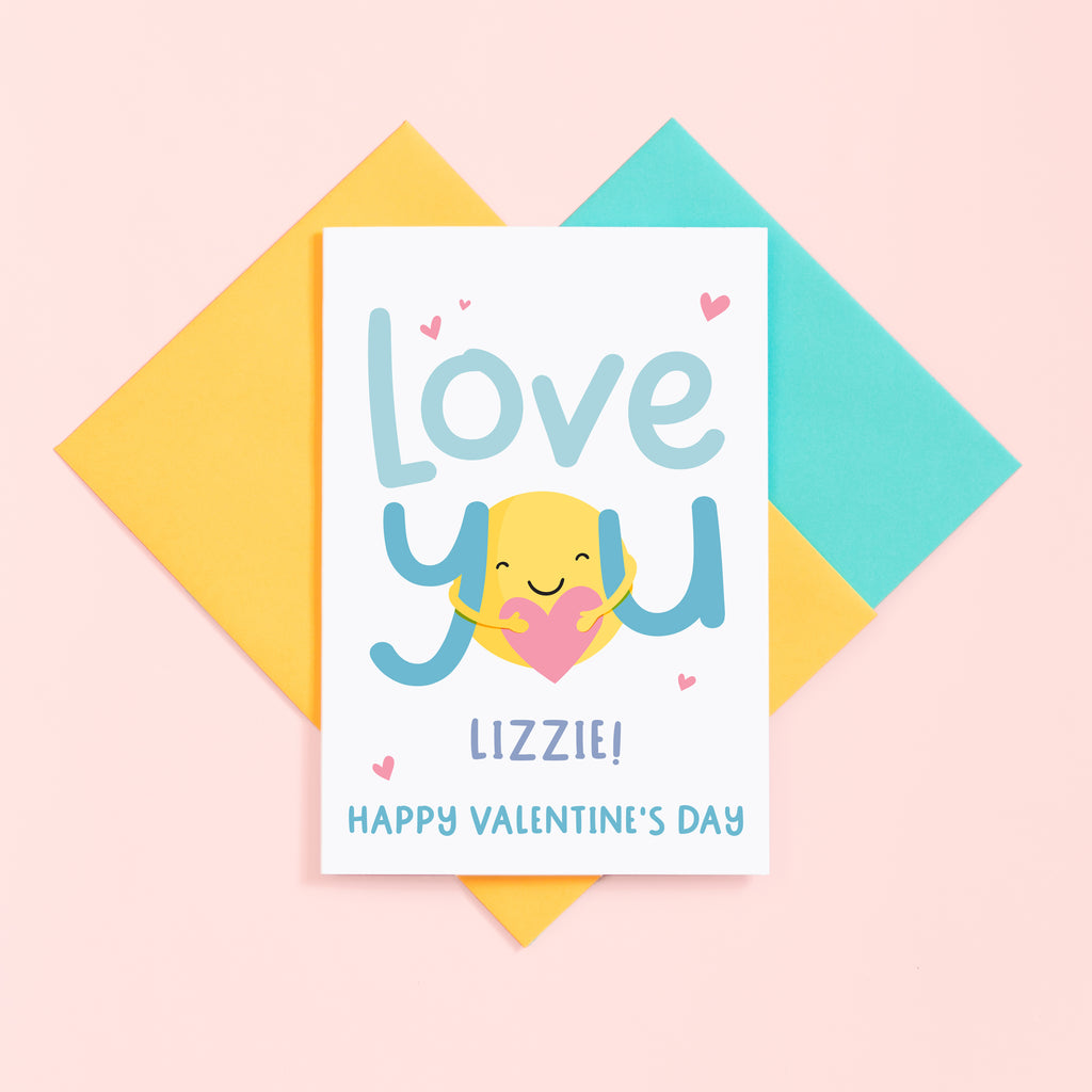 A super cute valentines card with the words 'love you' in turquoise and featuring a sunshine hug holding a heart. This card can be personalised with a name.