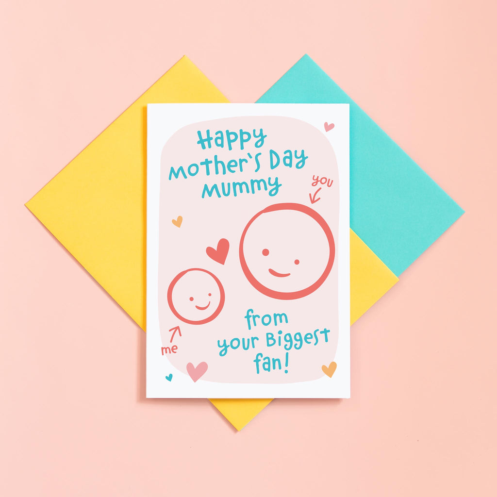 A cute Mother's day card for Mummy from her biggest fan. This card features a smiling face representing Mummy and a childs faces which can be personalised with their name. The background of the card is light pink and includes a collection of hearts around the design.