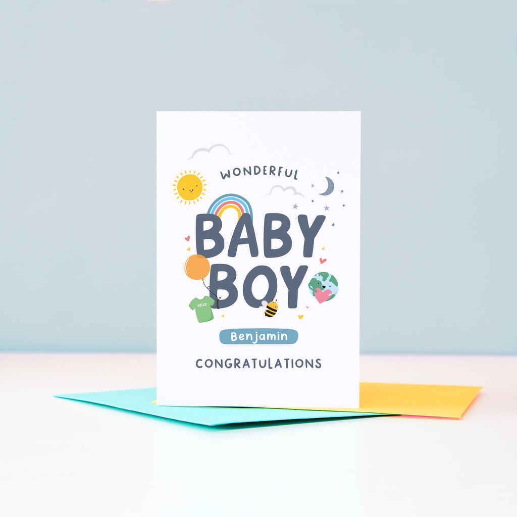 Wonderful Baby Boy Congratulations. A cute and colourful card featuring mini illustrations of a sunshine, rainbow, moon, stars, world holding a heart, balloon, tshirt and bee. This card has space to personalise with the baby's name.