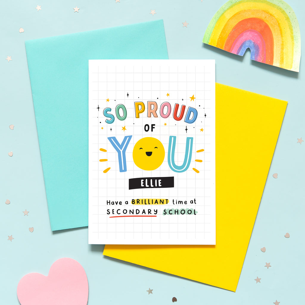 A bright and colourful secondary school card which reads, 'so proud of you have a brilliant time at secondary school'. The card features a happy face and stars and can be personalised with a name.