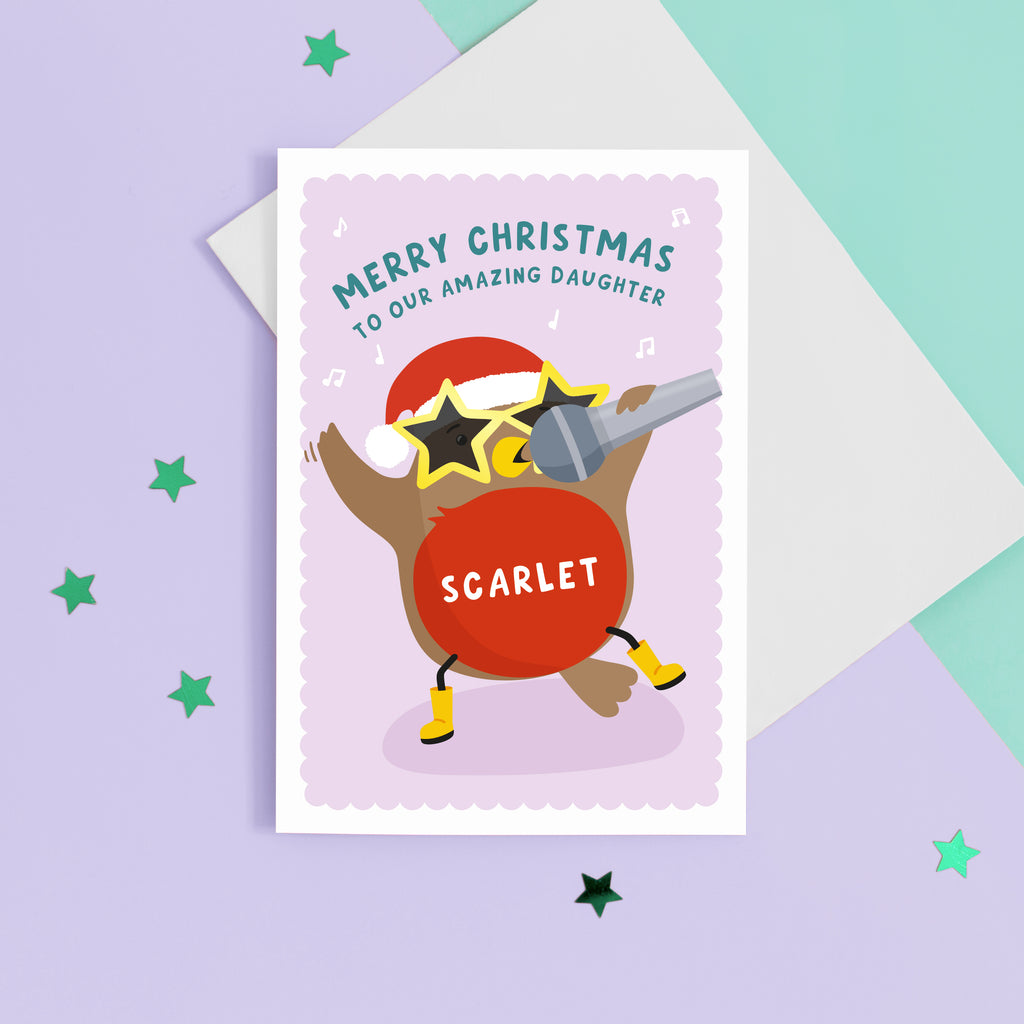 A colourful and fun card featuring a dancing and singing robin wearing a santas hat, big star glasses and wellies. The card reads ‘Merry Christmas to our Amazing Daughter with space to personalise with your Daughter’s name.