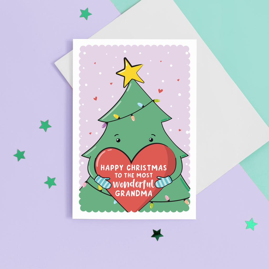 A cute Christmas card featuring a cartoon Christmas tree hugging a large love heart. The love heart reads, "Happy Christmas to the most wonderful Grandma". A yellow star is on the top of the tree set against a light purple snowy background with love hearts.
