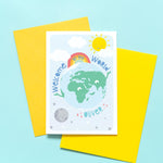 Load image into Gallery viewer, Greetings card with smiling earth character plus sun, moon and rainbow. text says welcome to the world and includes any personalised name in turquoise
