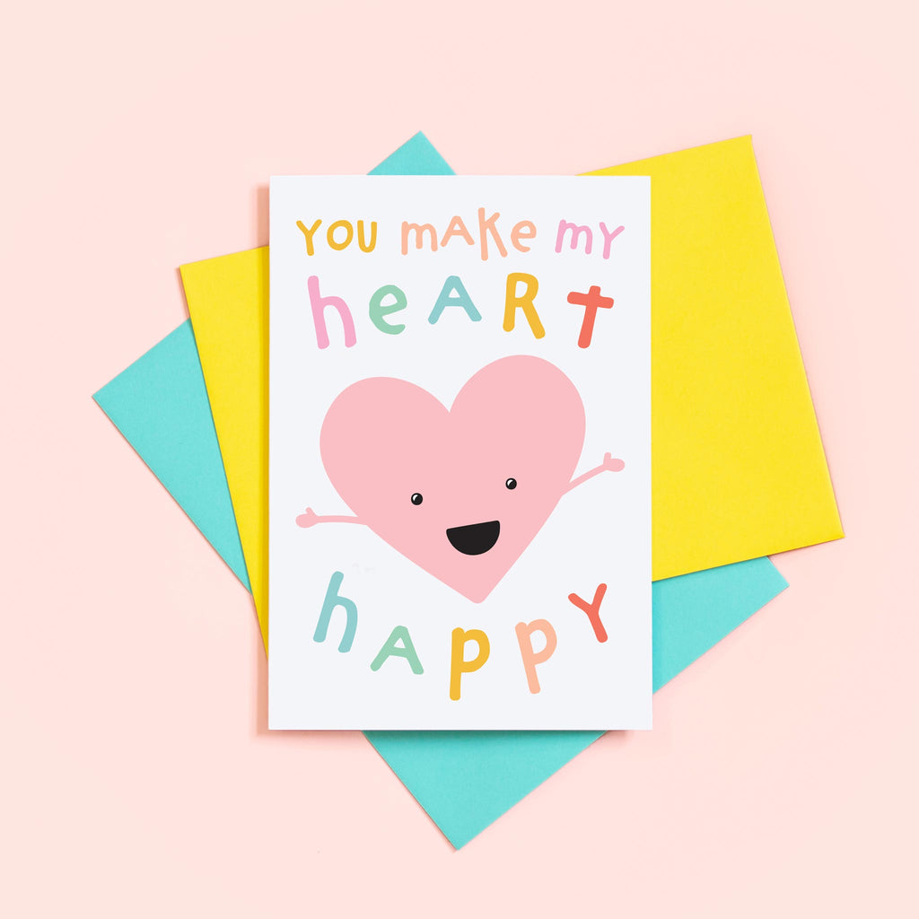 You make my heart happy card featuring colourful text and a cute smiling love heart with open arms.