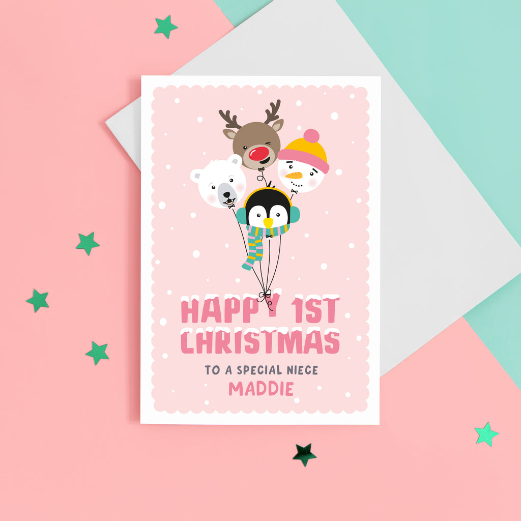 A super cute Christmas card featuring a bunch of happy balloon animals - reindeer, polar bear, penguin and snowman on a soft pink background. Featuring the words Happy 1st Christmas with a space for personalising the card for a special recipient.