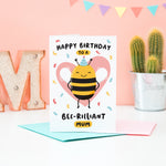 Load image into Gallery viewer, Happy birthday to a bee-rilliant mum. A cute and punny card featuring a happy bee wearing a party hat to represent mum, with a pink heart in the background and a sprinkle of confetti.
