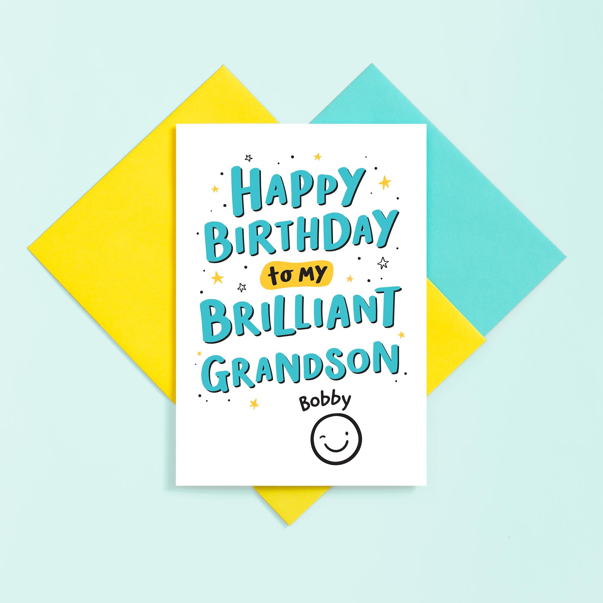 A hand lettered typographic card for a brilliant Grandson. The card features a collection of stars around the text and can be personalised with a name above a winking smiley face.