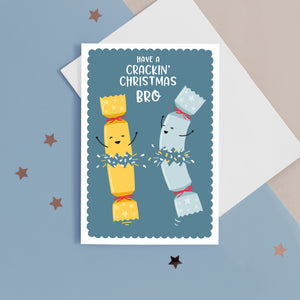 A funny Christmas card with a blue background, featuring two happy Christmas crackers and the words 'have a crackin' Christmas Bro'.