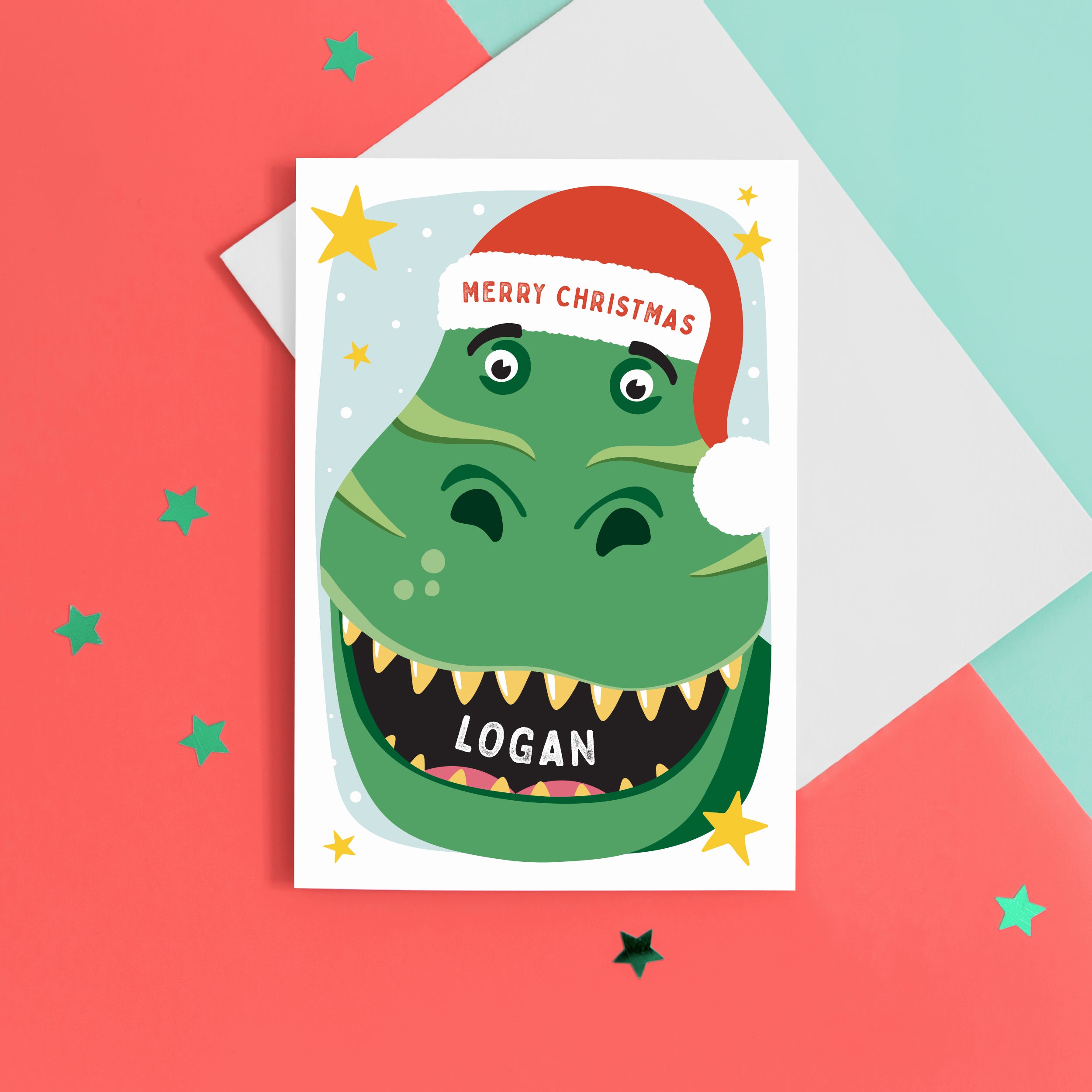 A bold and fun Christmas card featuring the face of a dinosaur with a big grin, wearing a red santas hat. The card reads Merry Christmas and is personalised with the child's name.