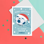 Load image into Gallery viewer, A fun football themed Christmas card featuring a happy football wearing a santa’s hat on a snowy background. The card reads ‘Merry Christmas to a super Sister’ with space underneath to personalise with a name.
