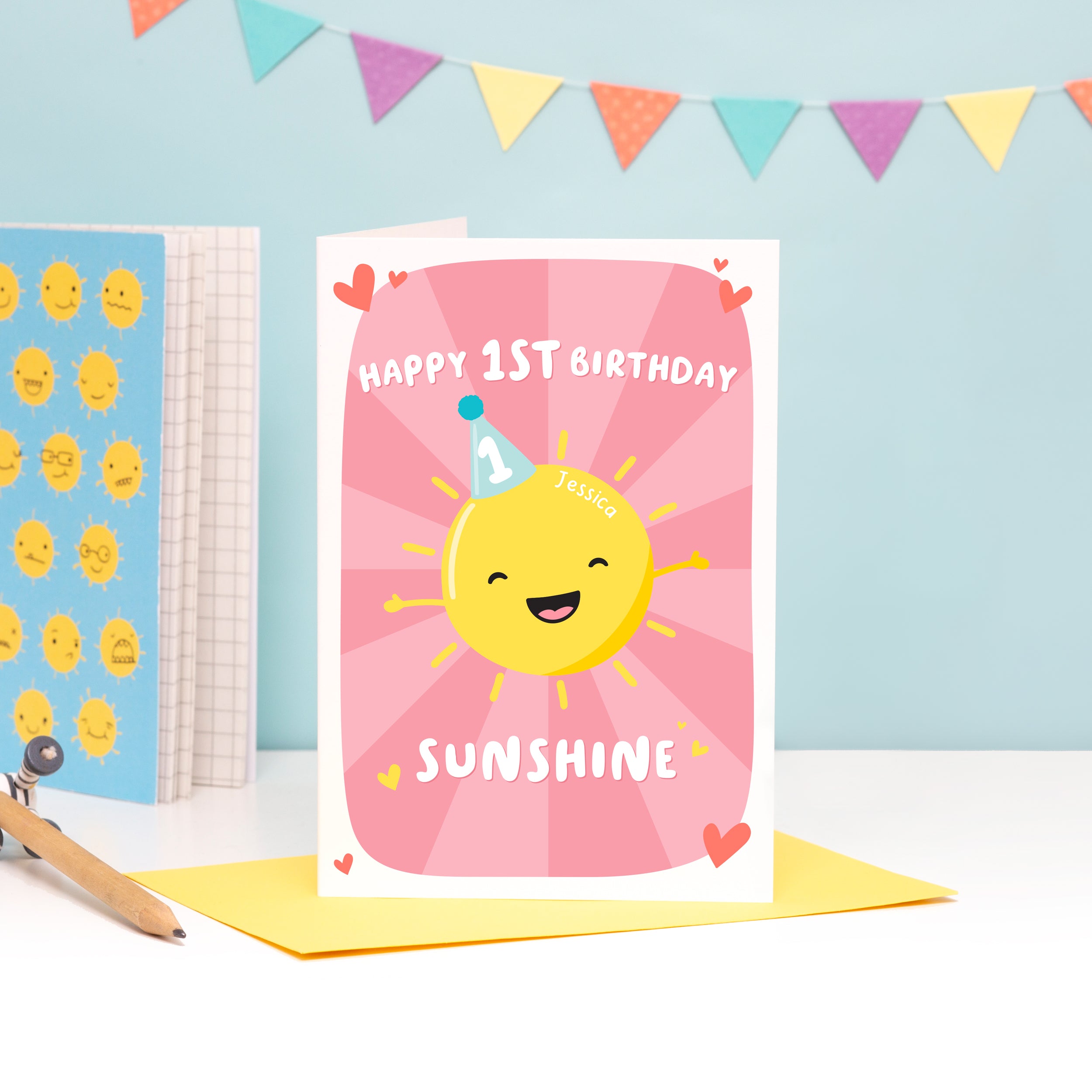 A colourful and fun design featuring a happy sunshine wearing a party hat with the number 1 on it. The card reads’ happy 1st birthday sunshine’ and you can add the childs name to the sunshine. The card has a colourful pink starburst background.