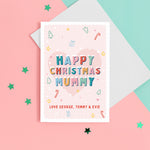 Load image into Gallery viewer, A sweet Christmas card with a pink background and small handrawn illustrations of Christmas trees, presents, stars and hearts. The card details colourful snowtopped wording reading Happy Christmas Mummy. The bottom of the card can be customised with your own message.
