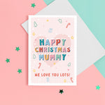 Load image into Gallery viewer, A sweet Christmas card with a pink background and small handrawn illustrations of Christmas trees, presents, stars and hearts. The card details colourful snowtopped wording reading Happy Christmas Mummy. The bottom of the card can be customised with your own message.
