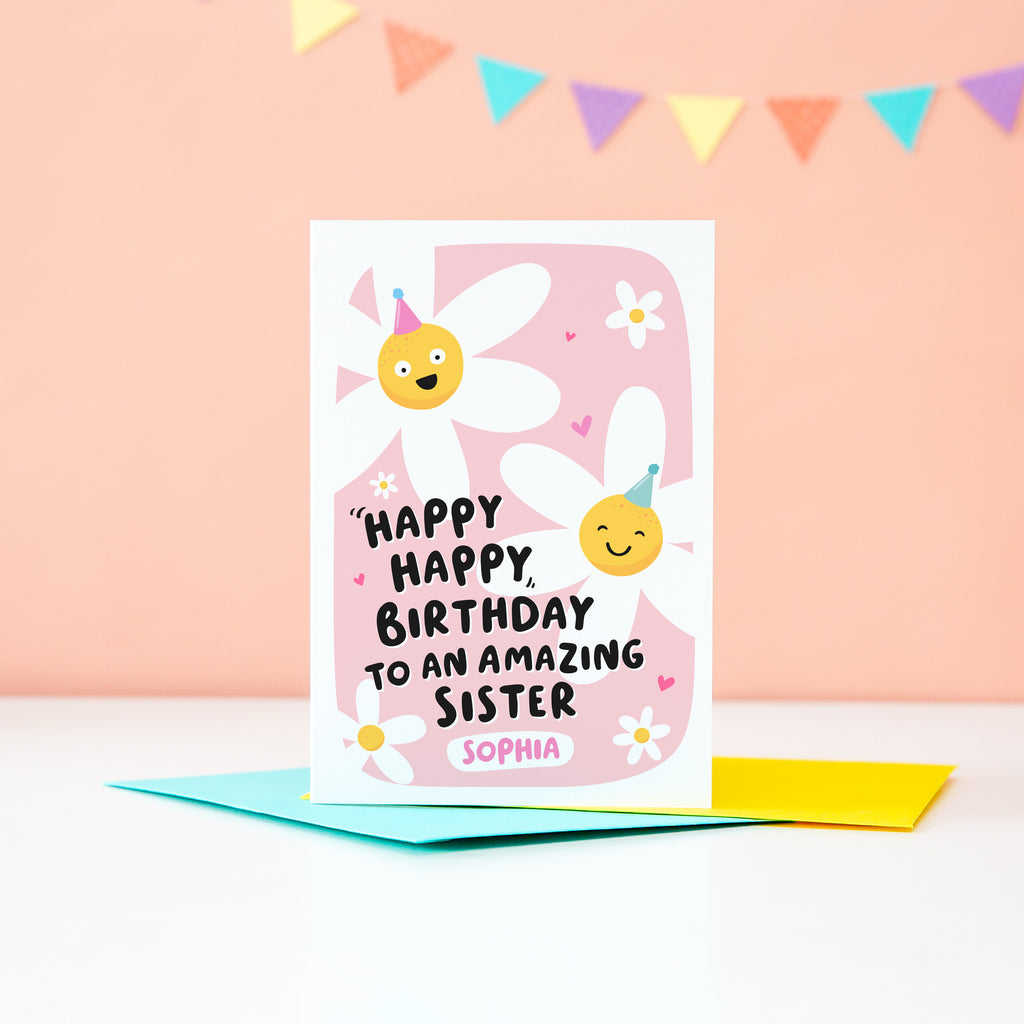 A cute card with a pink background, featuring happy daisies wearing party hats and the words, happy happy birthday to an amazing Sister. There is space underneath the text to personalise with Sister's name.