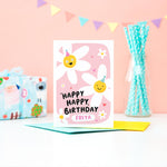 Load image into Gallery viewer, A cute card with a pink background featuring two happy daisies wearing party hats, a few hearts and the words happy happy birthday with space for personalisation underneath.
