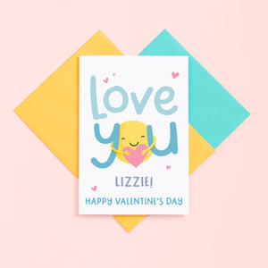 A super cute valentines card with the words 'love you' in turquoise and featuring a sunshine hug holding a heart. This card can be personalised with a name.