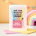 Load image into Gallery viewer, A colourful birthday card featuring a bright rainbow and confetti exploding out of a gift box. The rainbow features text in front saying &#39;hope your special day is full of magic&#39; and the box says Happy Birthday.
