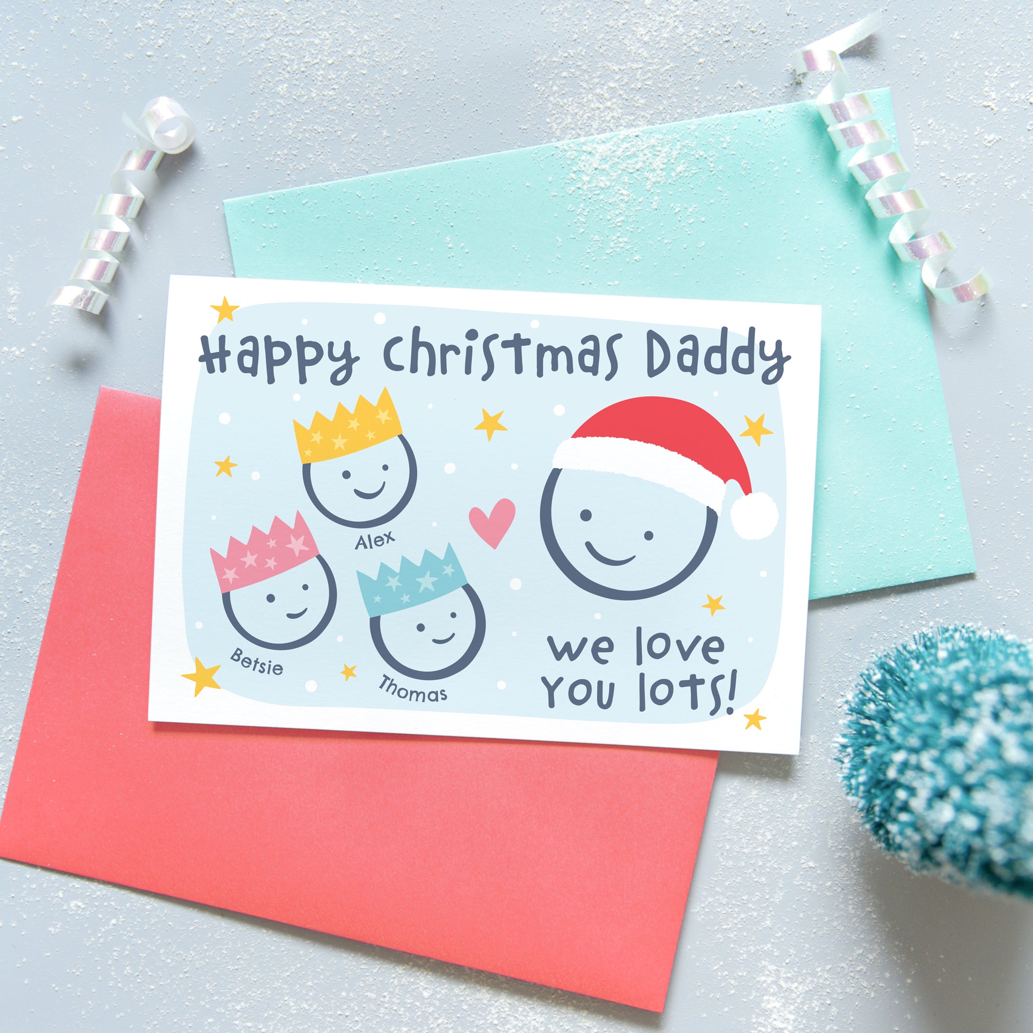 Happy Christmas Daddy, we love you lots. Cute Christmas card featuring 4 faces representing Daddy and 3 children. The smaller faces wear Christmas party hats and the larger face a santa hat. The card is personalised with the children's names and has a soft blue background.