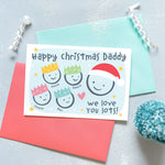 Load image into Gallery viewer, Happy Christmas Daddy, we love you lots. Cute Christmas card featuring 5 faces representing Daddy and 4 children. The smaller faces wear Christmas party hats and the larger face a santa hat. The card is personalised with the children&#39;s names and has a soft blue background.
