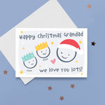 Load image into Gallery viewer, Happy Christmas Grandad, we love you lots. Cute Christmas card featuring 3 faces representing Grandfather and 2 grandchildren. The smaller faces wear Christmas party hats and the larger face a santa hat. The card is personalised with the children&#39;s names and has a soft grey background.
