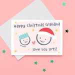 Load image into Gallery viewer, Happy Christmas Grandma, love you lots. Cute Christmas card featuring 2 faces representing Grandmother and Grandchild. The smaller face wears a Christmas party hat and a larger face a santa hat. The card is personalised with the child&#39;s name and has a soft pink background.
