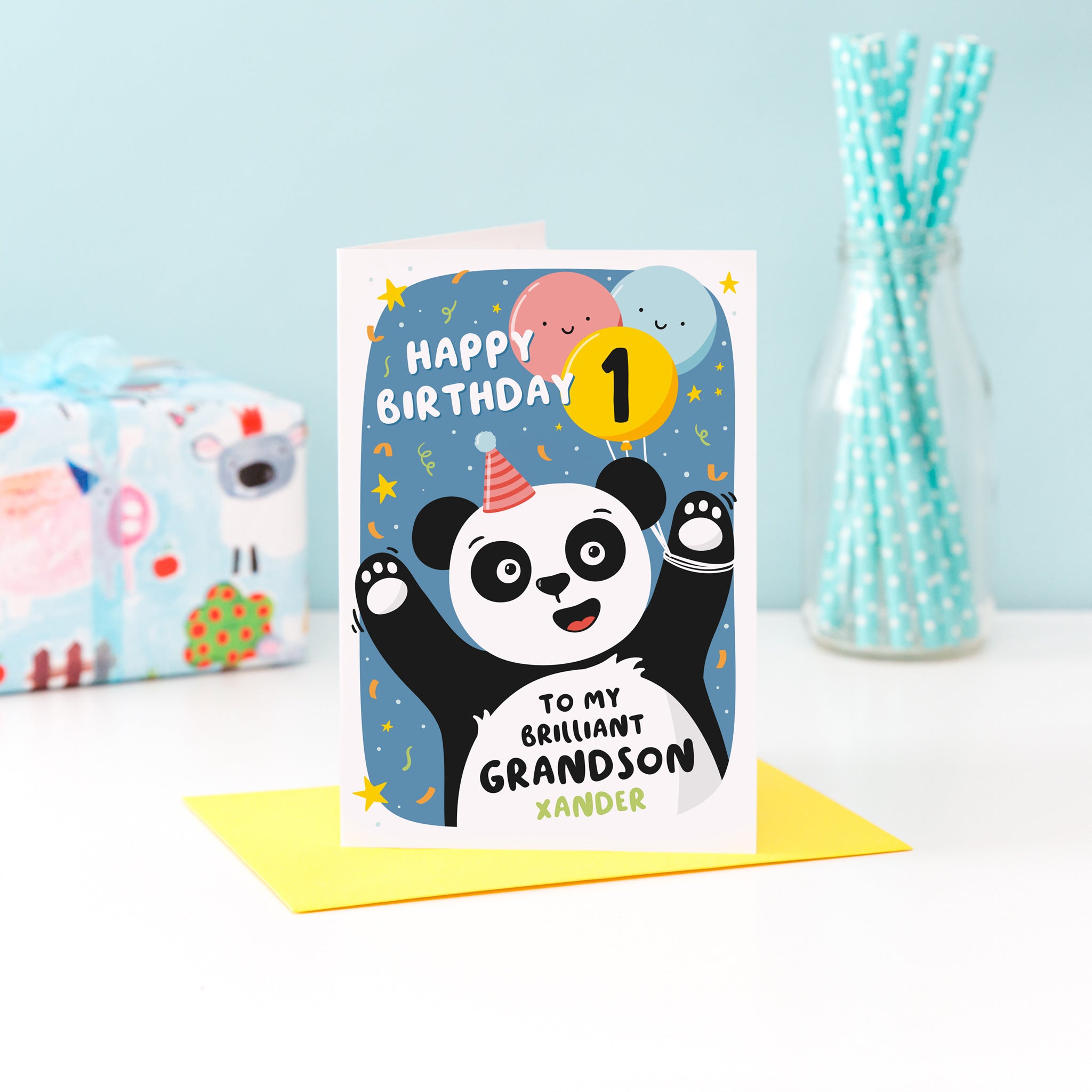 A fun and colourful card featuring a happy panda wearing a party hat, a collection of smiling balloons and a pop of confetti. The card reads happy birthday to my brilliant grandson with space to personalise with a name. There is also space on a balloon to add the childs age.