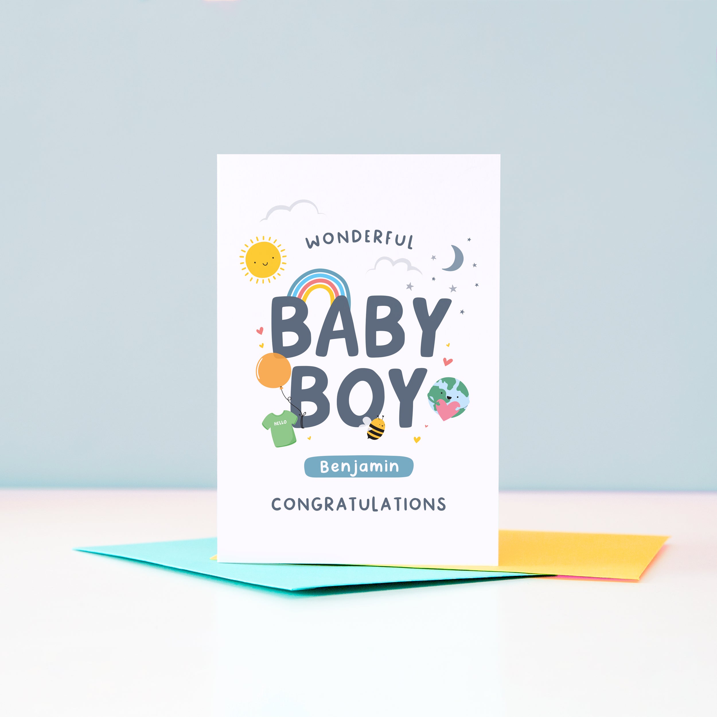 Wonderful Baby Boy Congratulations. A cute and colourful card featuring mini illustrations of a sunshine, rainbow, moon, stars, world holding a heart, balloon, tshirt and bee. This card has space to personalise with the baby's name.