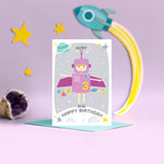 Load image into Gallery viewer, Space girl happy birthday card. This fun and colourful card shows a little girl dressed up as a purple space rocket with arms out. The card also features a moon, planets and stars. The card is personalised with any name and age.
