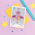 Load image into Gallery viewer, Space girl happy birthday card. This fun and colourful card shows a little girl dressed up as a purple space rocket with arms out. The card also features a moon, planets and stars. The card is personalised with any name and age.
