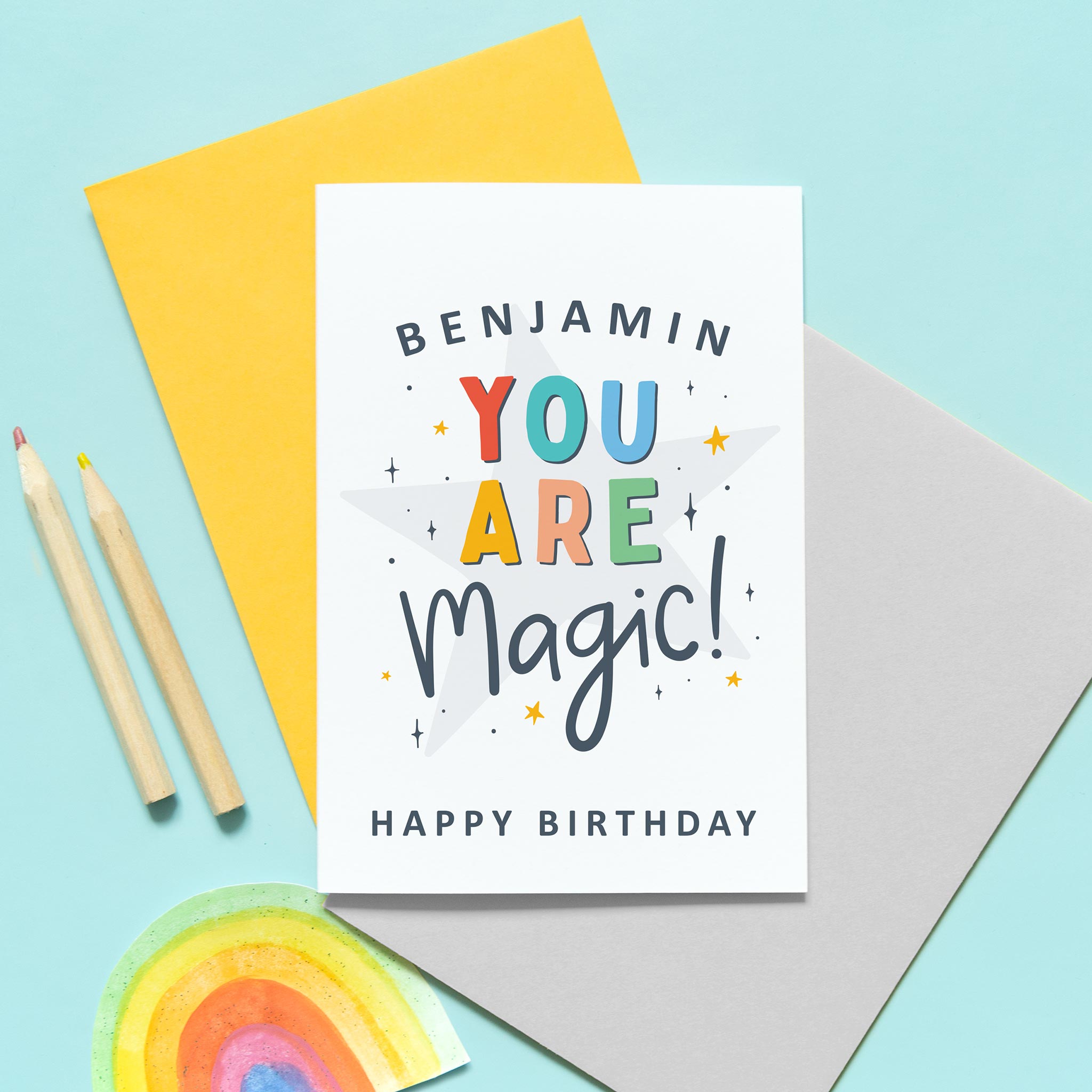 A colourful typographic card with a personalised name and the words 'you are magic! Happy birthday'. The card features a large light grey star in the background with a collection of smaller stars around the lettering.