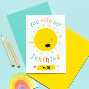 You are my sunshine card with personalised name. This cute and colourful card features a smiling happy sun and the popular quote.